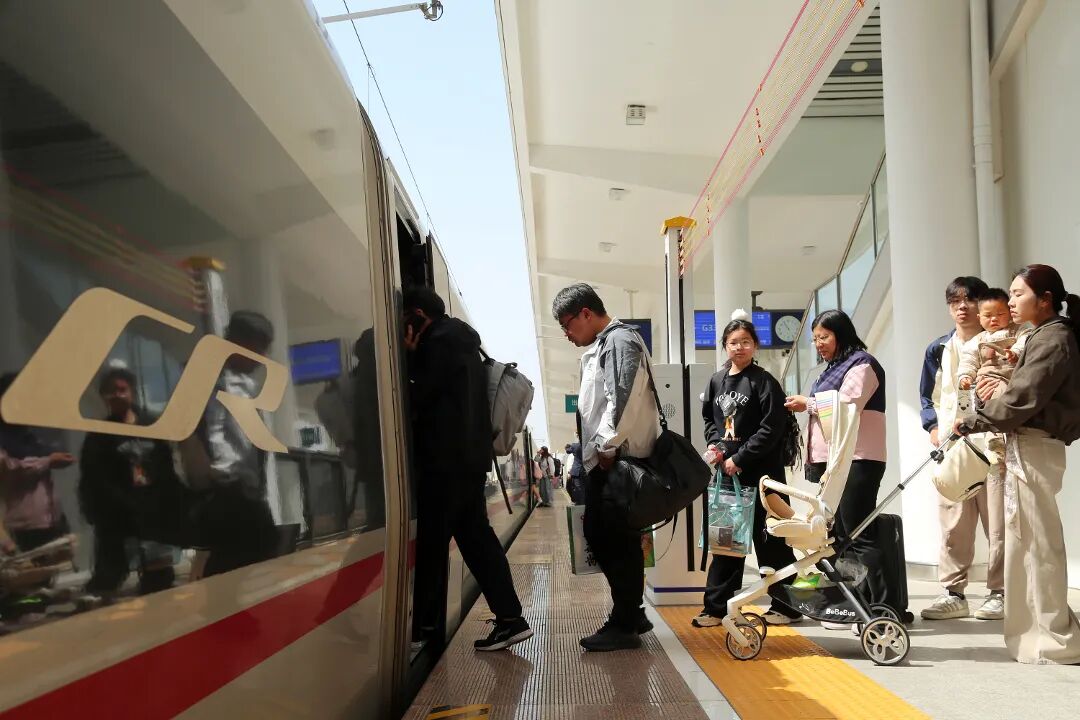 Passengers boarding a China Railway high-speed train on the platform with the CR logo visible