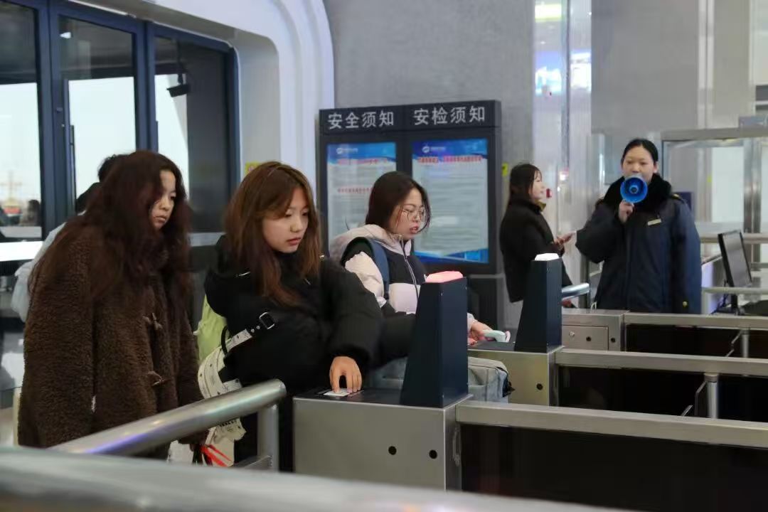 Passengers at the secondary entry gates with Safety Notice / Security Inspection Notice signage behind them