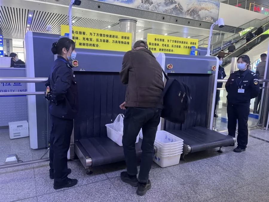 Security X-ray scanner with yellow signs listing prohibited items: liquids, power banks, pressurized containers, knives
