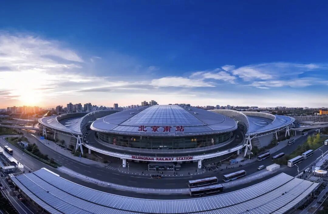 The elliptical roof of Beijing South Railway Station seen from above at sunset.