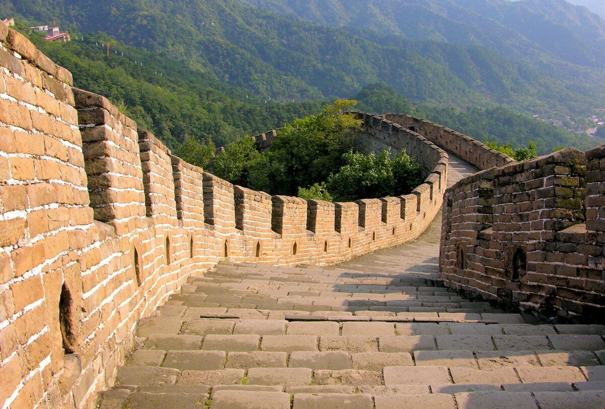 Jinshanling Great Wall section — watchtowers and crumbling battlements along a mountain ridge at sunrise.