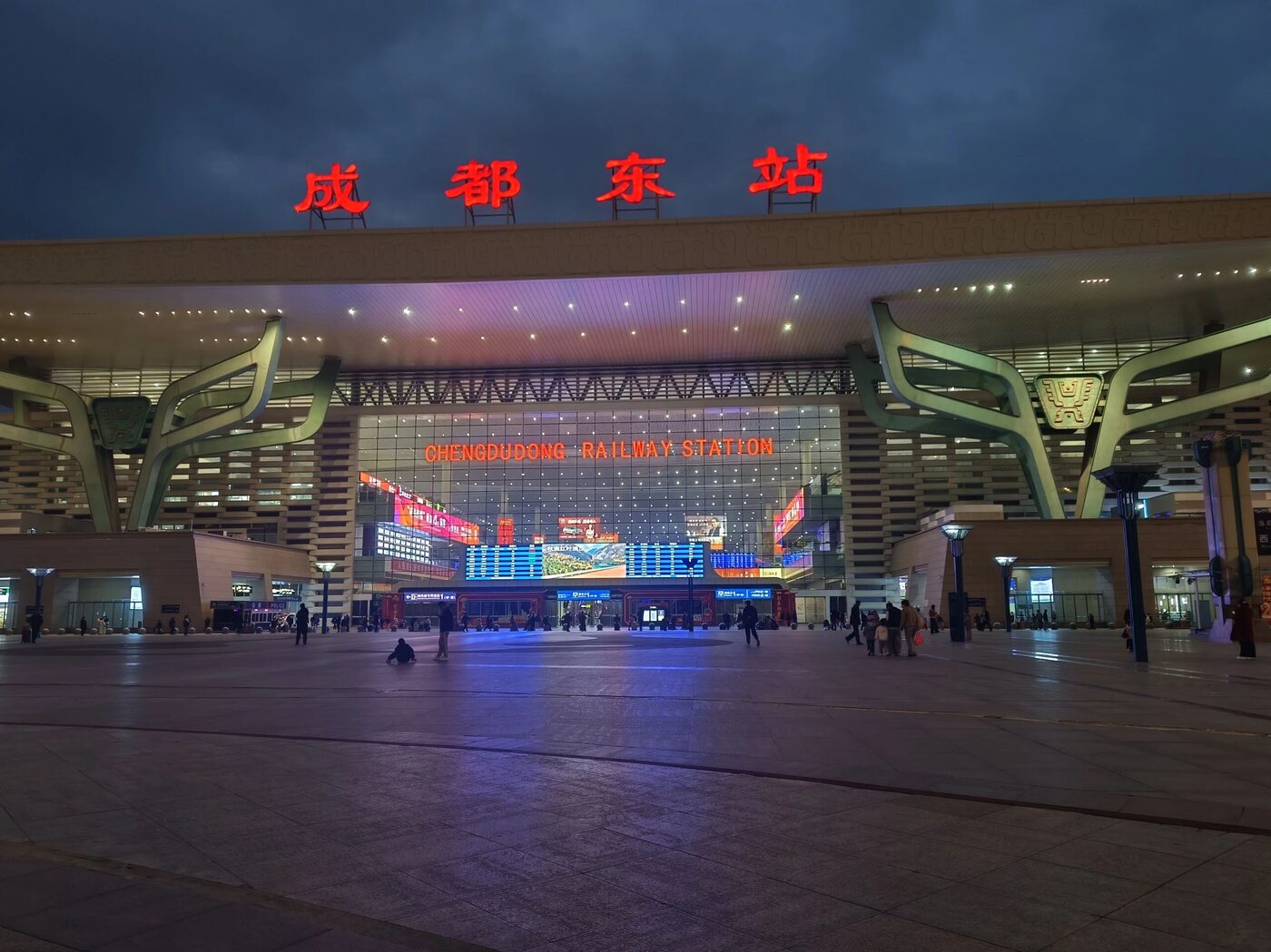The illuminated facade of Chengdu East Railway Station at dusk with its station-front plaza.
