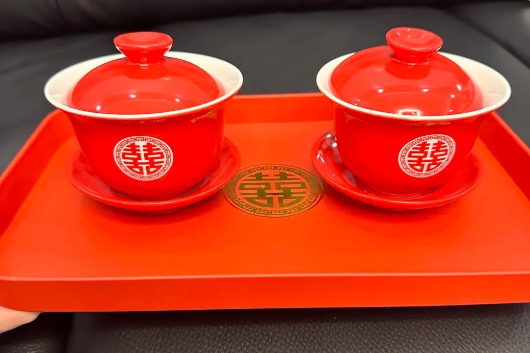 A pair of red lidded tea bowls marked with the double-happiness character on a red lacquer tray