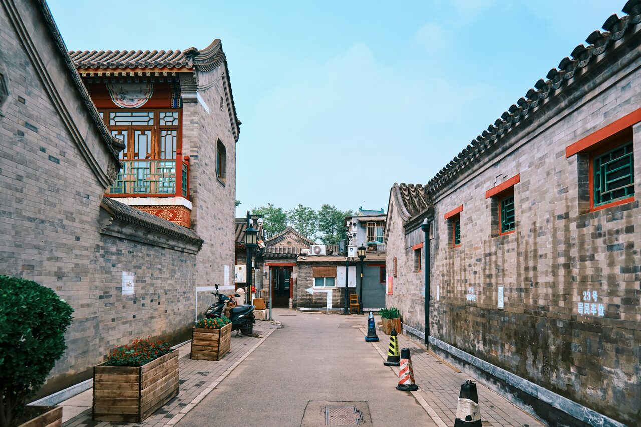 Narrow hutong alley with traditional grey-brick courtyard houses, central Beijing.