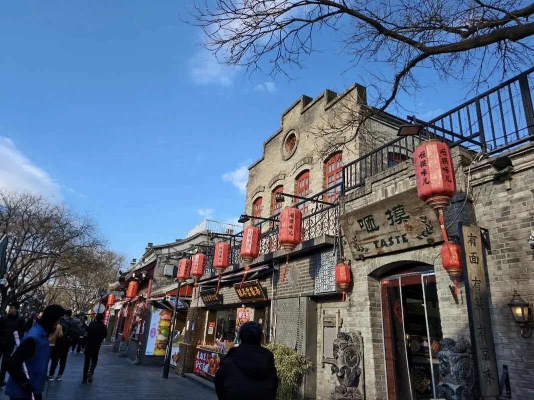 The restored Nanluoguxiang lane in Beijing with shopfronts, lanterns and visitors.
