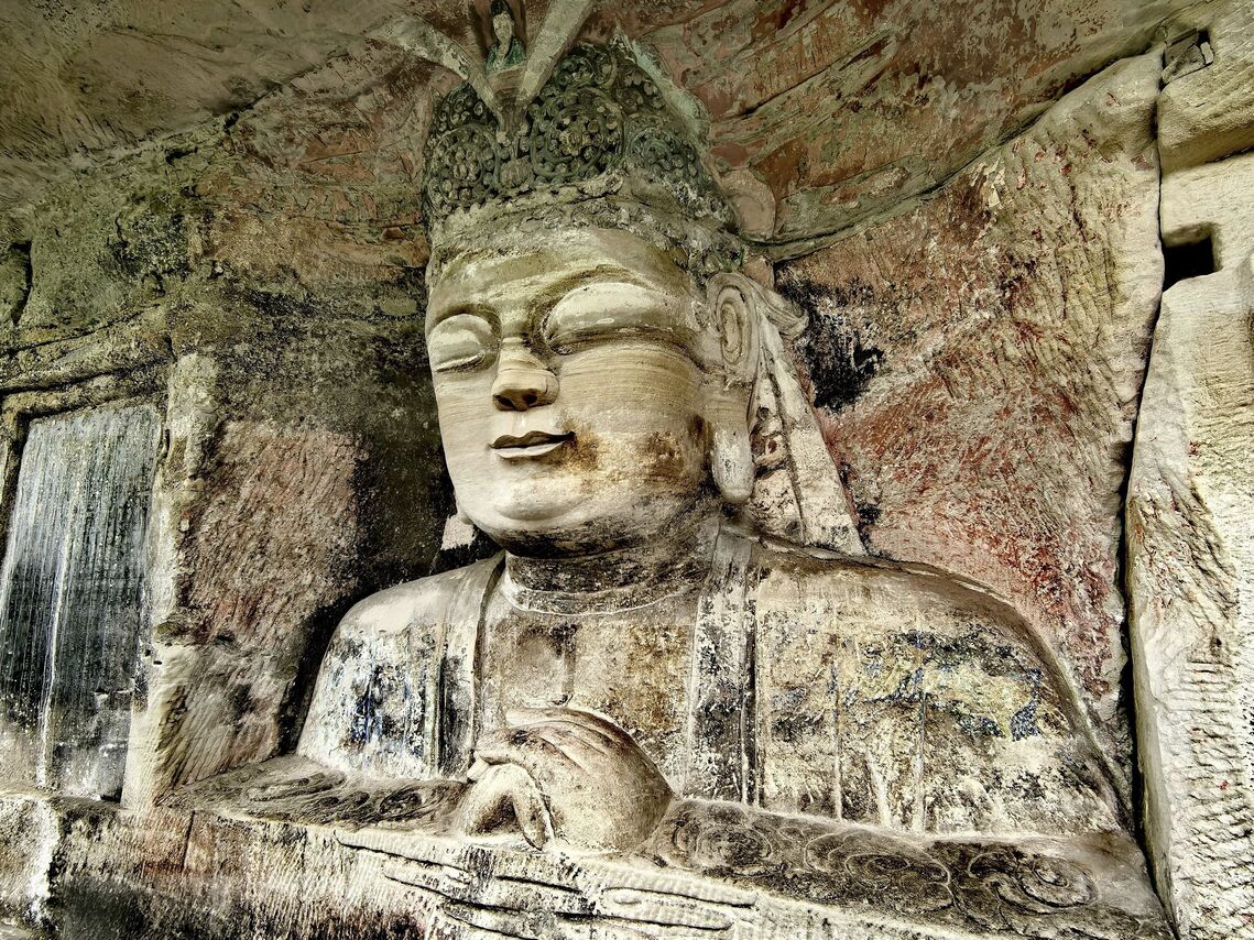 Close-up of a large serene Buddha figure carved into the sandstone cliff at Dazu Rock Carvings, Chongqing.