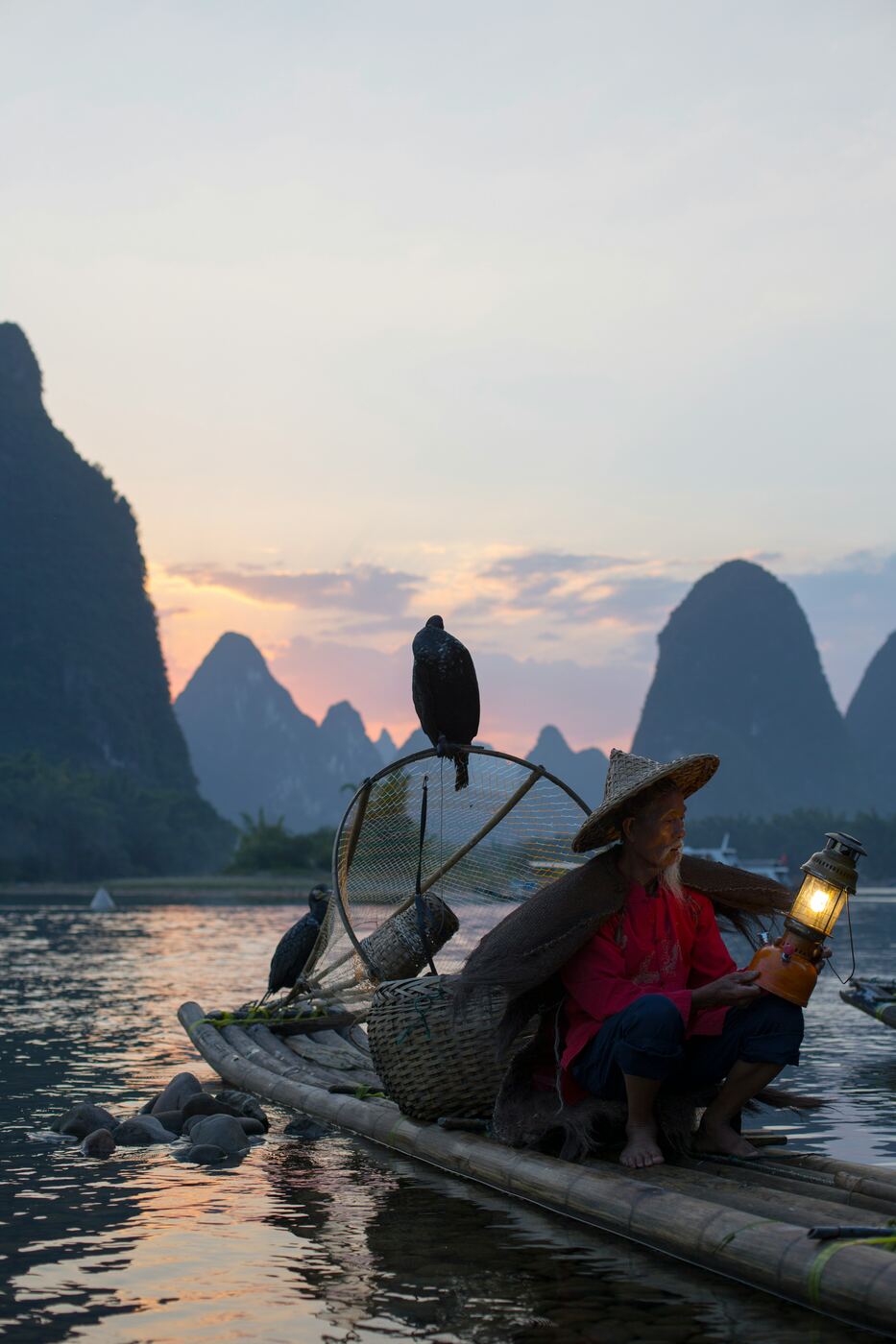 A fisherman with cormorants on a bamboo raft at dusk on the Li River near Xingping.