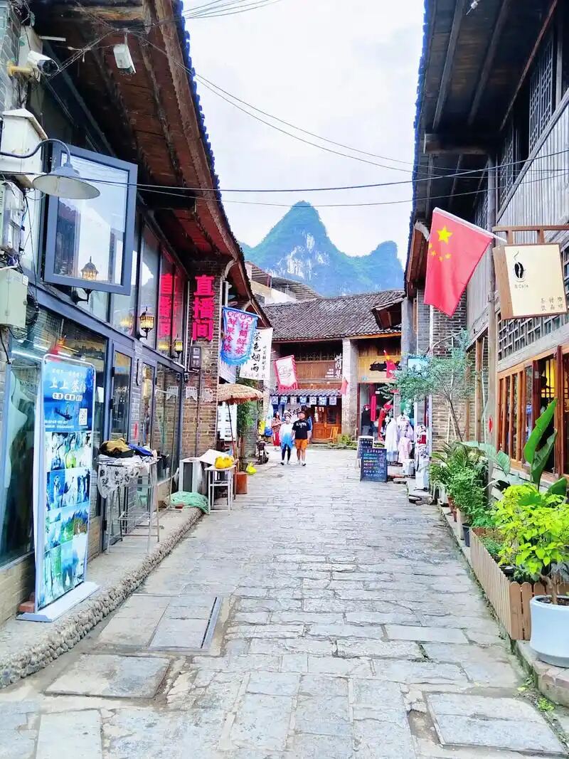 A stone-paved old street lined with shops and hanging banners in Xingping ancient town near Yangshuo.