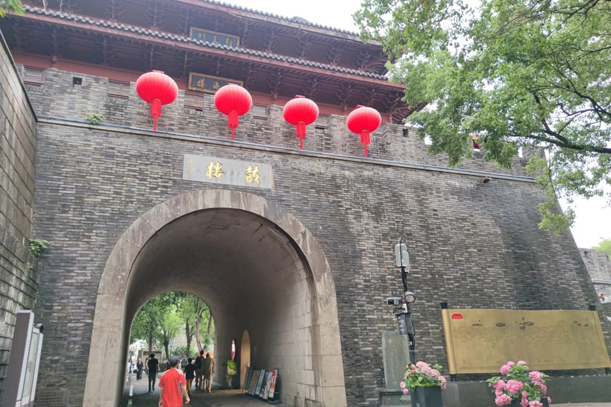 The Drum Tower at Qinghefang in Hangzhou — a grey stone gate with an arched passage, four large red lanterns hung across its face and a timber tower above.