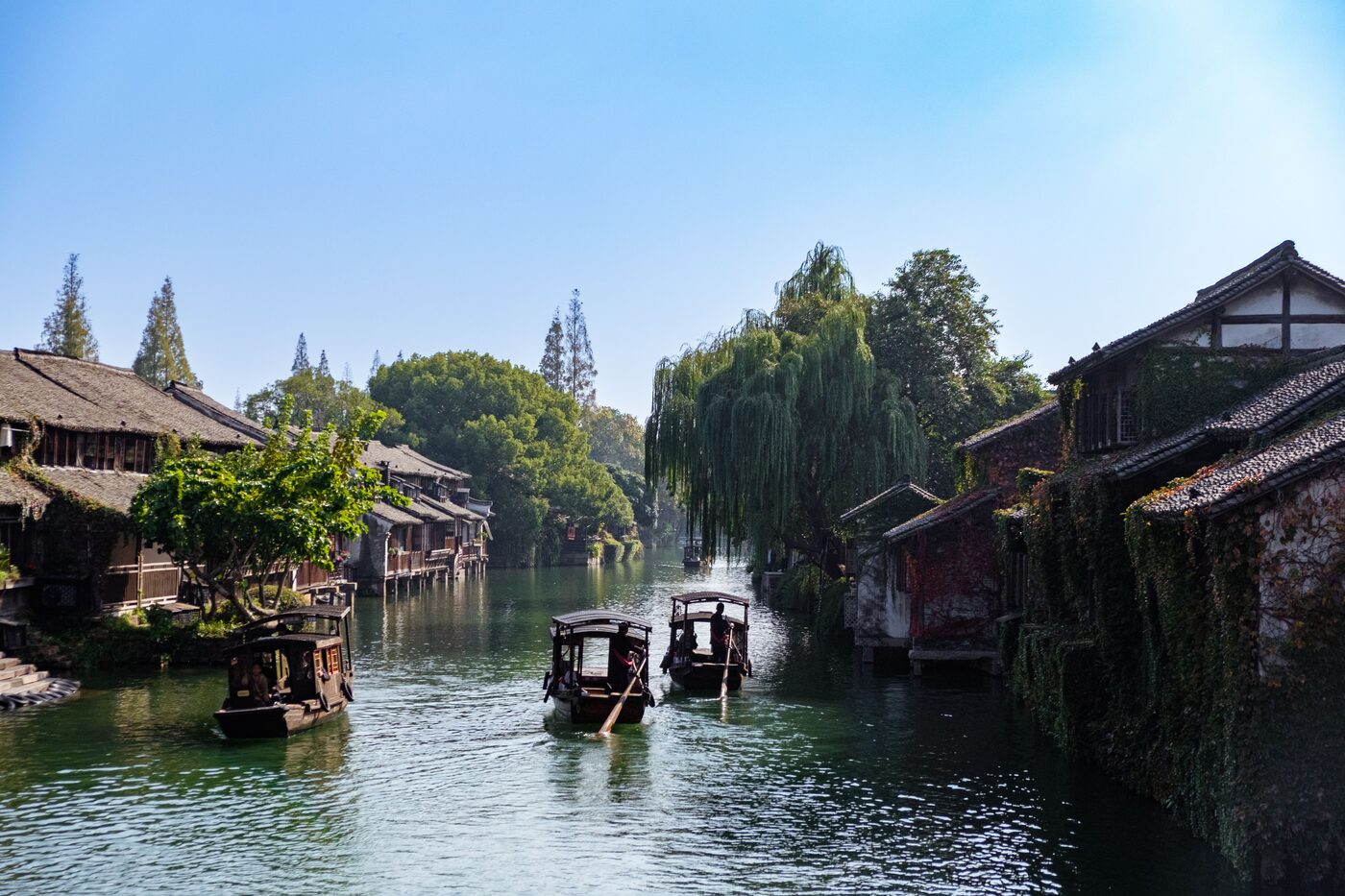 Wuzhen water town near Hangzhou — whitewashed canal houses, stone bridges and boats at dusk.