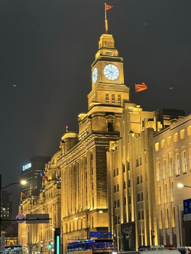 The Bund waterfront at night with Pudong skyline lit up across the Huangpu River.