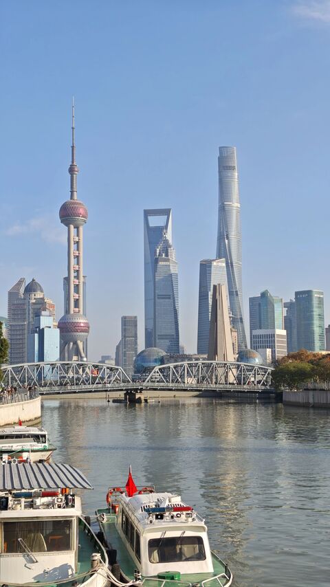 An evening sightseeing boat on the Huangpu River, Shanghai, with the lit Bund and Pudong skylines on either bank.