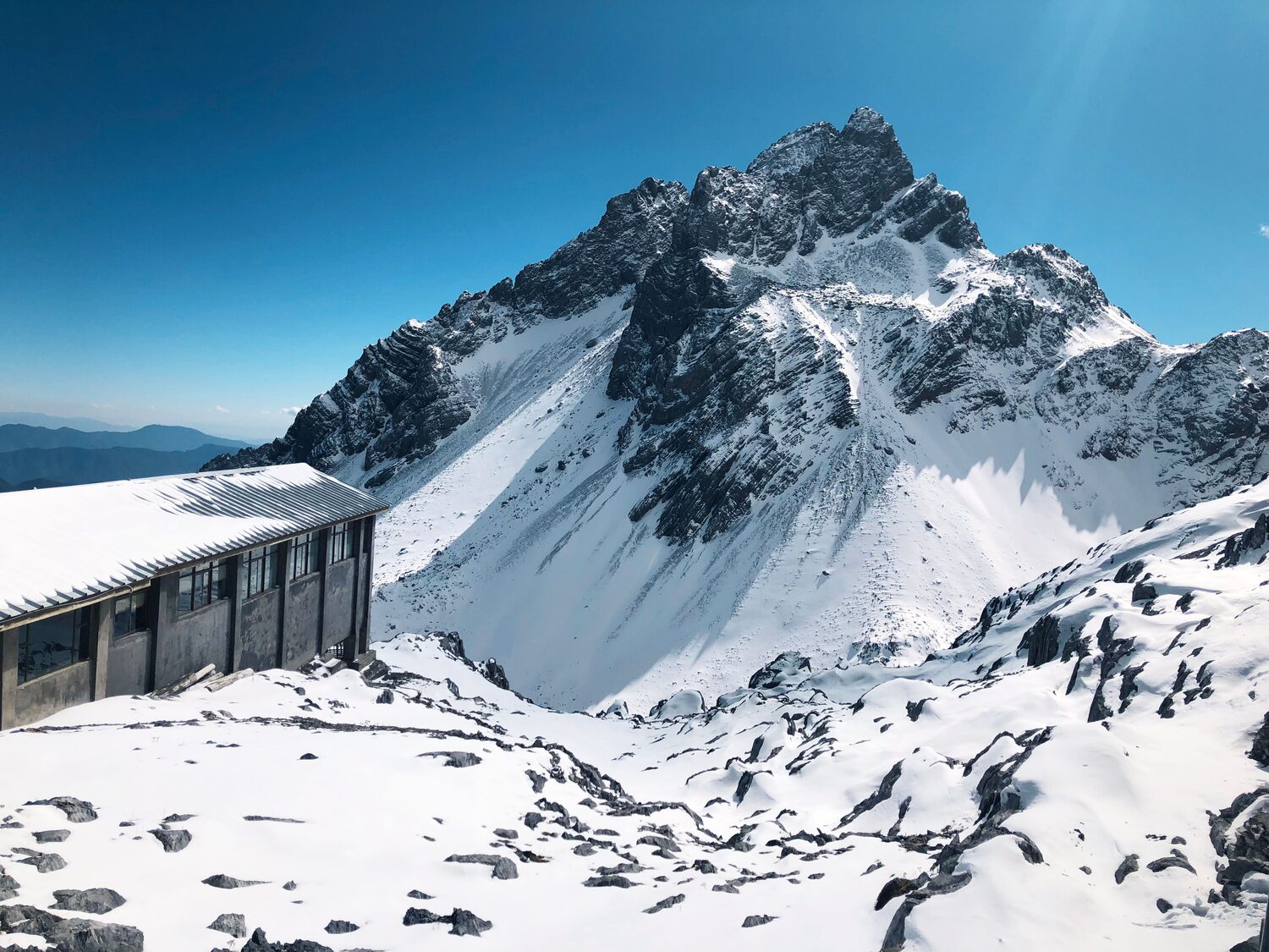 The Big Cable Car upper terminal building at Glacier Park, 4,506 m, with the snow peak of Jade Dragon Snow Mountain behind.