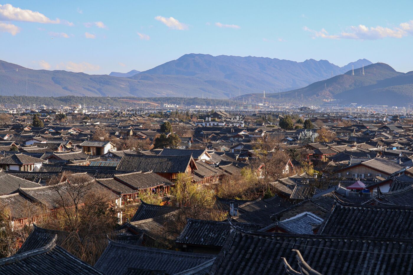 Lijiang Old Town in Yunnan — cobbled lanes, whitewashed Naxi courtyard houses and tiled roofs below the mountains.