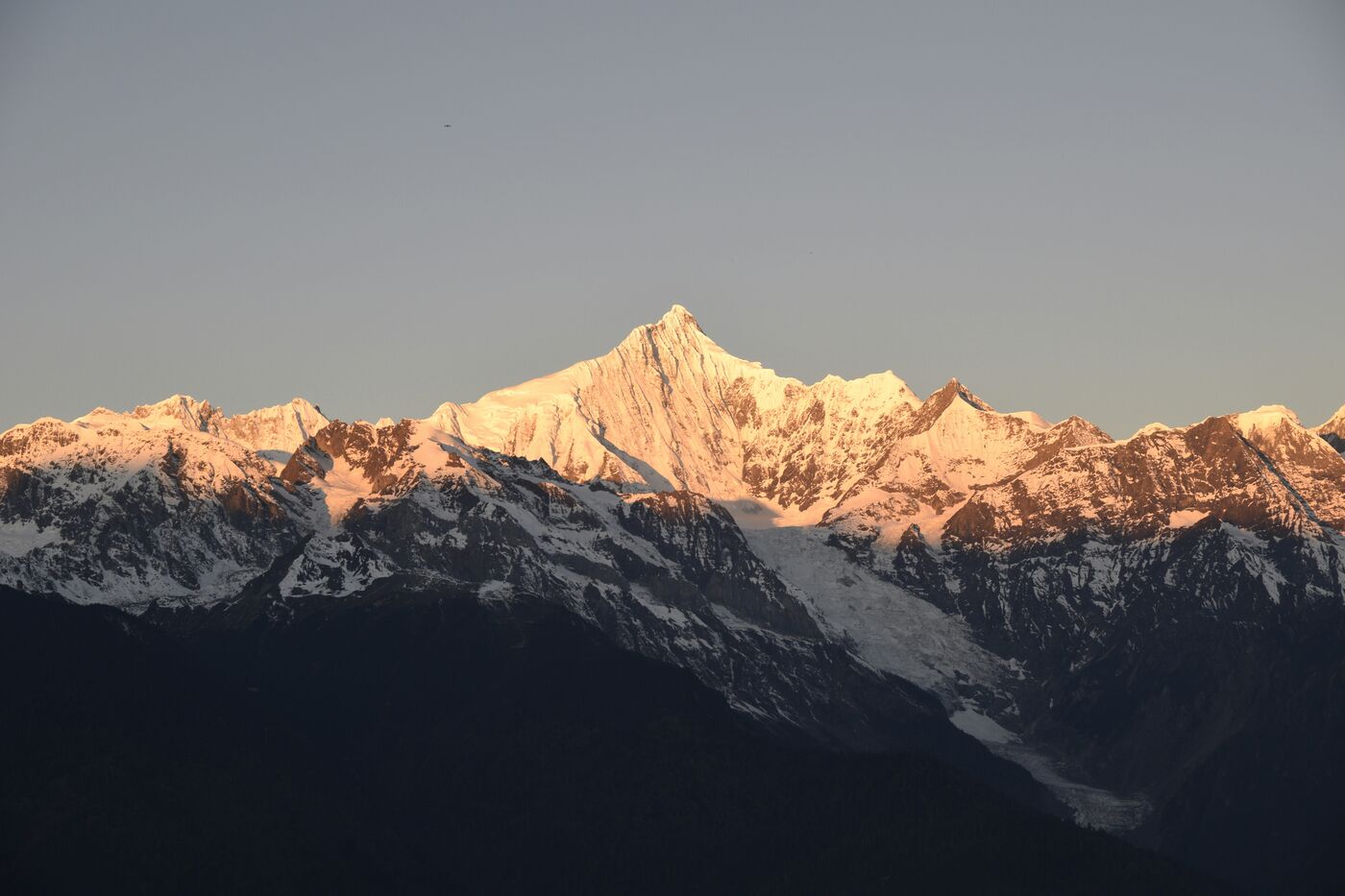 Meili Snow Mountain in Yunnan — a glaciated peak catching first light above deep valleys.