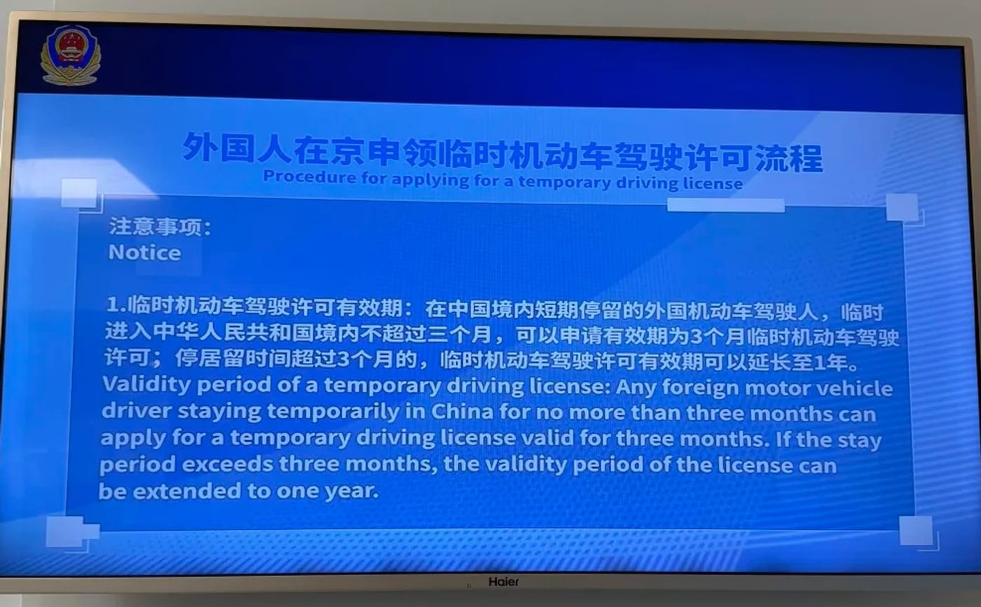 Police information screen at Beijing Daxing airport headed 'Procedure for applying for a temporary driving license', stating in Chinese and English that a foreign driver staying no more than three months can apply for a permit valid three months, extendable to one year if the stay exceeds three months.