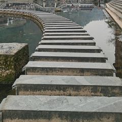 The famous stepping stones of Fenghuang crossing the green Tuojiang River by the North Gate, people crossing in single file.