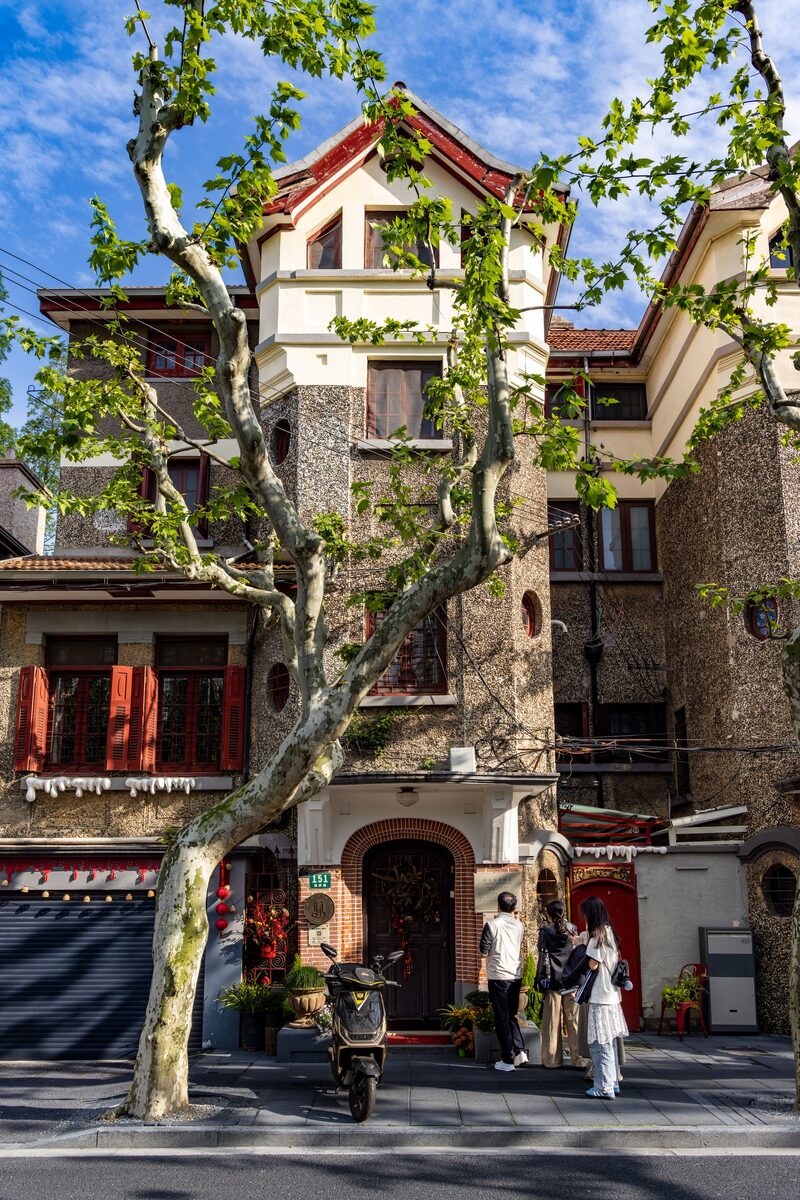 Plane-tree-lined street in the former French Concession, Shanghai, with a 1920s-30s villa and pedestrians.