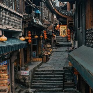 The worn stone-slab main street of Furong Ancient Town, lined with red lanterns, stilt-house shops and a wine-shop banner.
