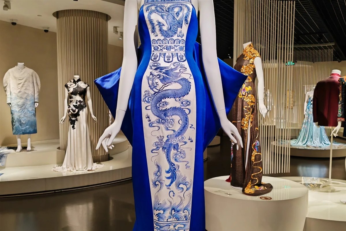 Mannequins in the museum's fashion gallery wearing modern silk gowns, including a long blue dress panelled with a blue-and-white dragon print.