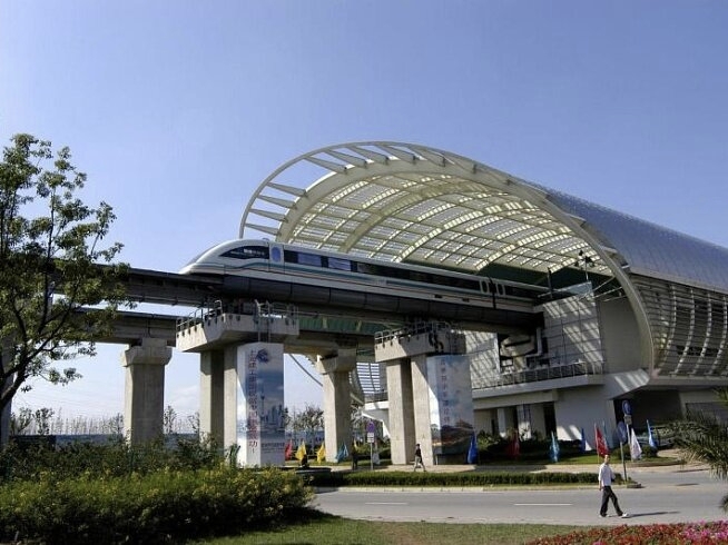 Longyang Road maglev station building — distinctive arched steel-and-glass roof, elevated platform structure, with the maglev train visible inside under the canopy