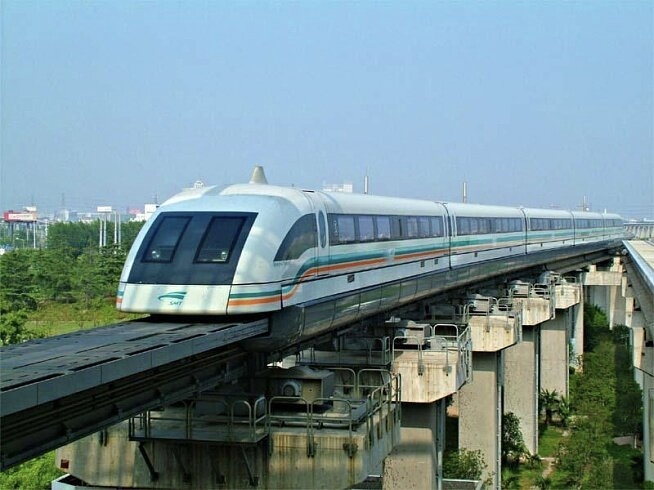 Shanghai Maglev train running on the elevated dedicated track between Pudong Airport and Longyang Road, viewed from below against suburban Pudong scenery