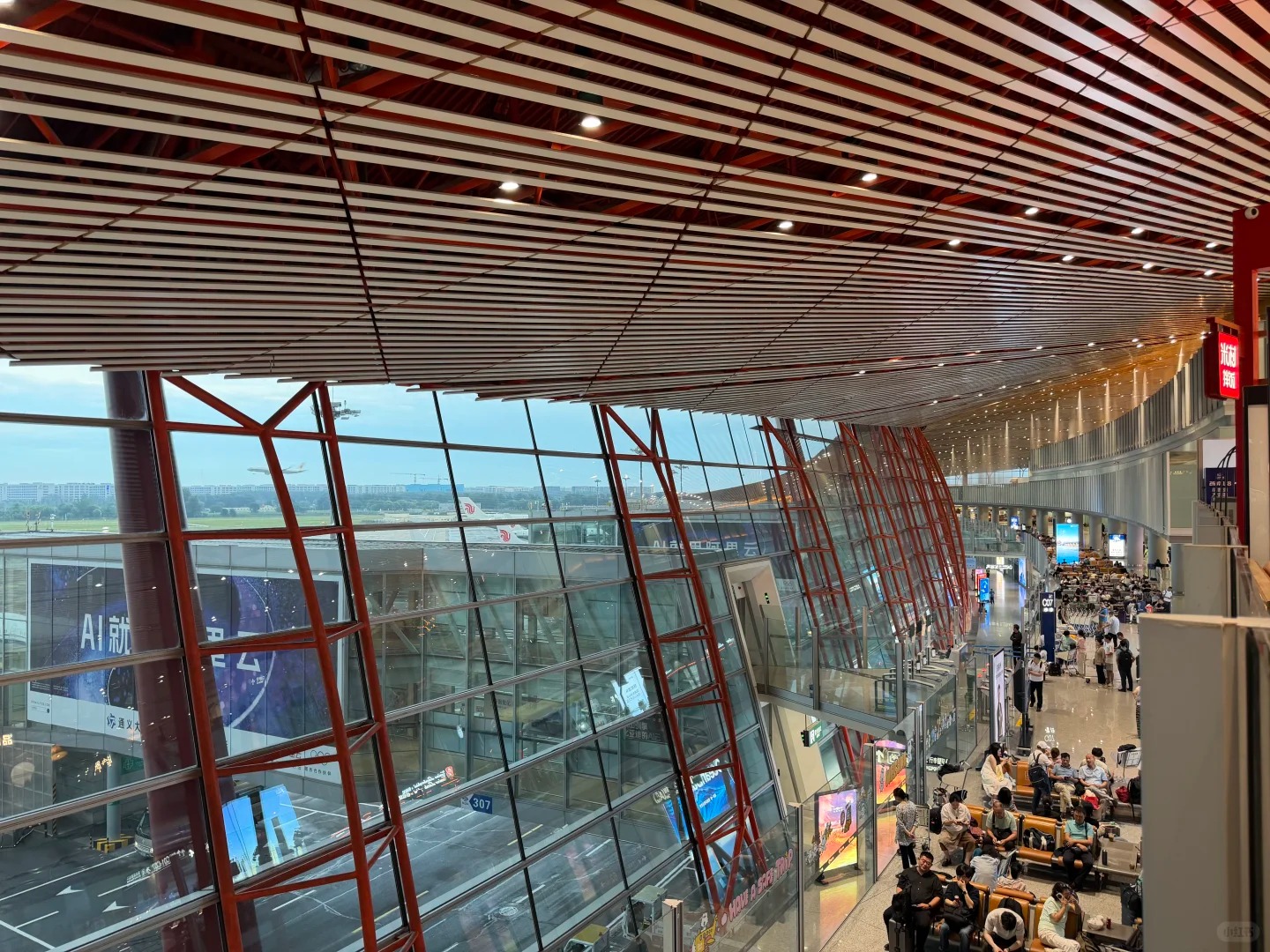 Terminal 3-E international concourse at Beijing Capital Airport under the red dragon-scale roof, with Air China aircraft at the gates