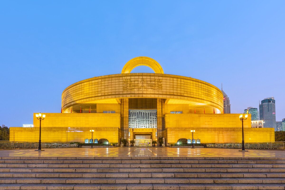 The Shanghai Museum on People's Square — a circular granite building modelled on an ancient bronze ding vessel, lit gold at dusk.