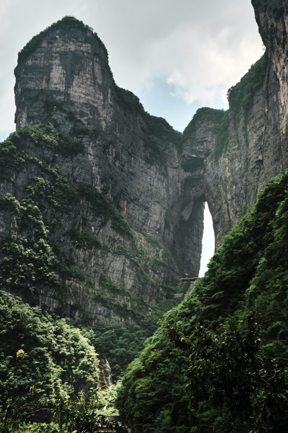 The Tianmen cave seen from the valley below — a vast natural arch punched through the cliff face of Tianmen Mountain, Zhangjiajie.