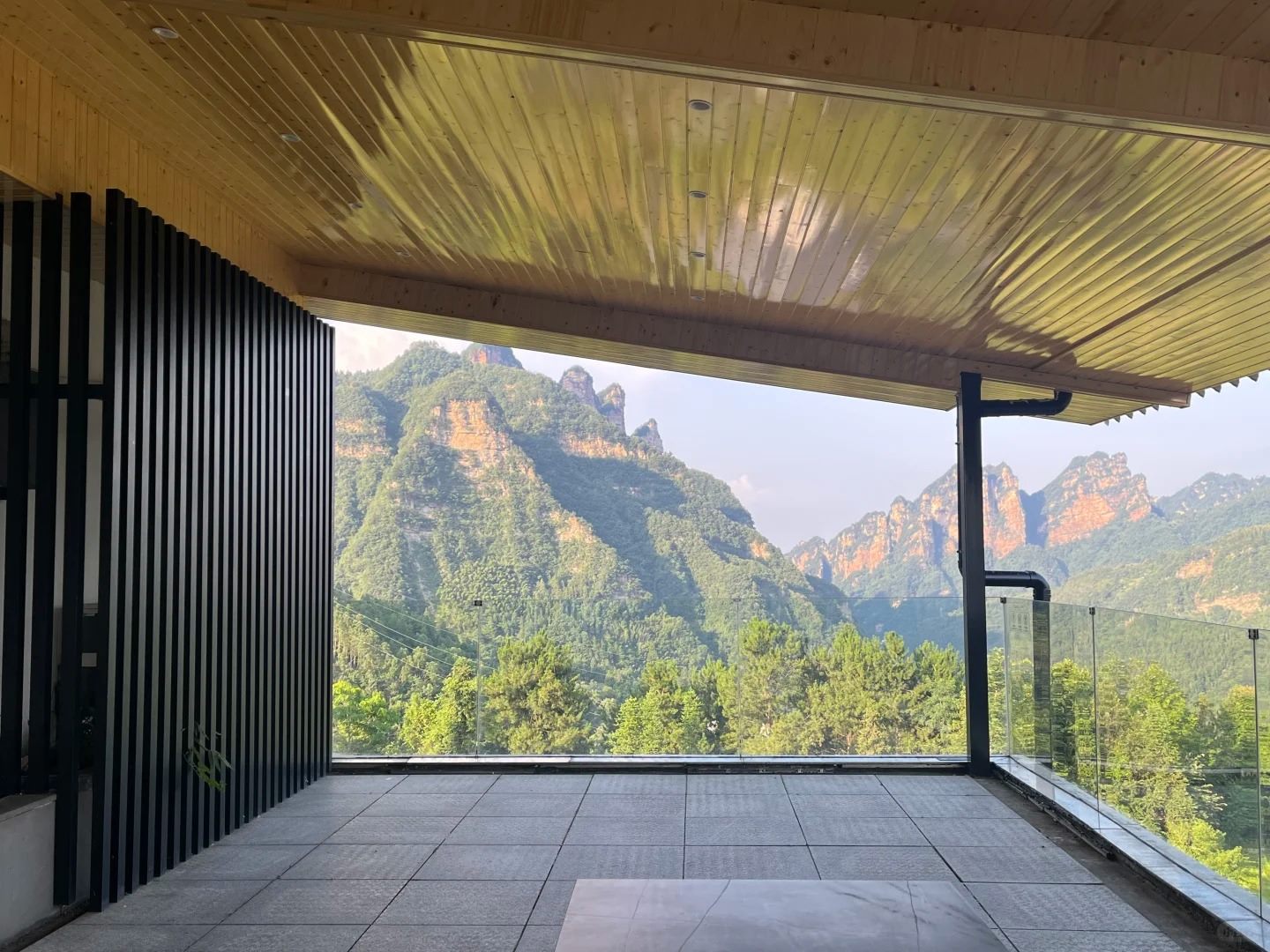 A guesthouse terrace inside the Zhangjiajie park area looking out at forested quartz-sandstone cliffs and pinnacle ridges.