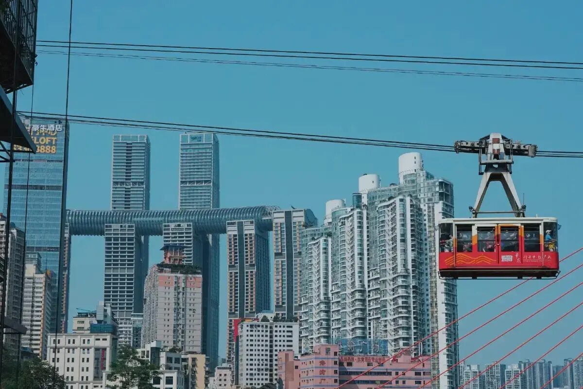 Yangtze Cable Car cabin with the Raffles City 'One Thousand Sets' horizontal skybridge and Chongqing high-rises behind it.