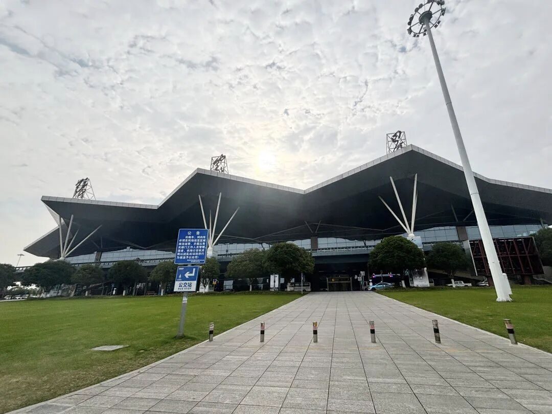 The terminal building of Zhangjiajie Hehua International Airport (DYG), with its mountain-wave roofline and forecourt bus stop.