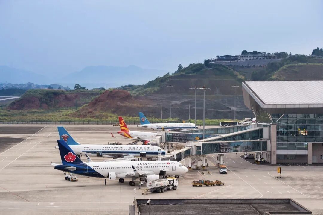 Domestic aircraft from China Southern, Hainan and Qingdao Airlines parked on the apron at Zhangjiajie Hehua Airport, with the surrounding hills behind.
