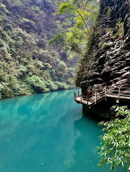A clear emerald pool and cliffside boardwalk along the Golden Whip Stream valley on the floor of Zhangjiajie's Wulingyuan park.