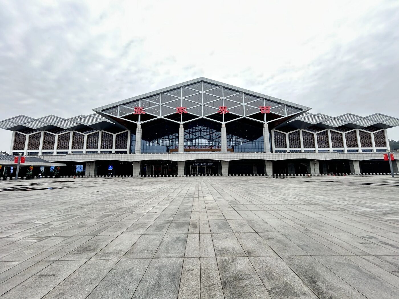 The large modern facade and forecourt plaza of Zhangjiajie West Railway Station, the city's high-speed-rail hub.